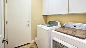 Una sala de lavandería con lavadora, secadora y armarios.