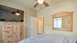 Un dormitorio con cama, cómoda, ventilador de techo y un espejo grande.
