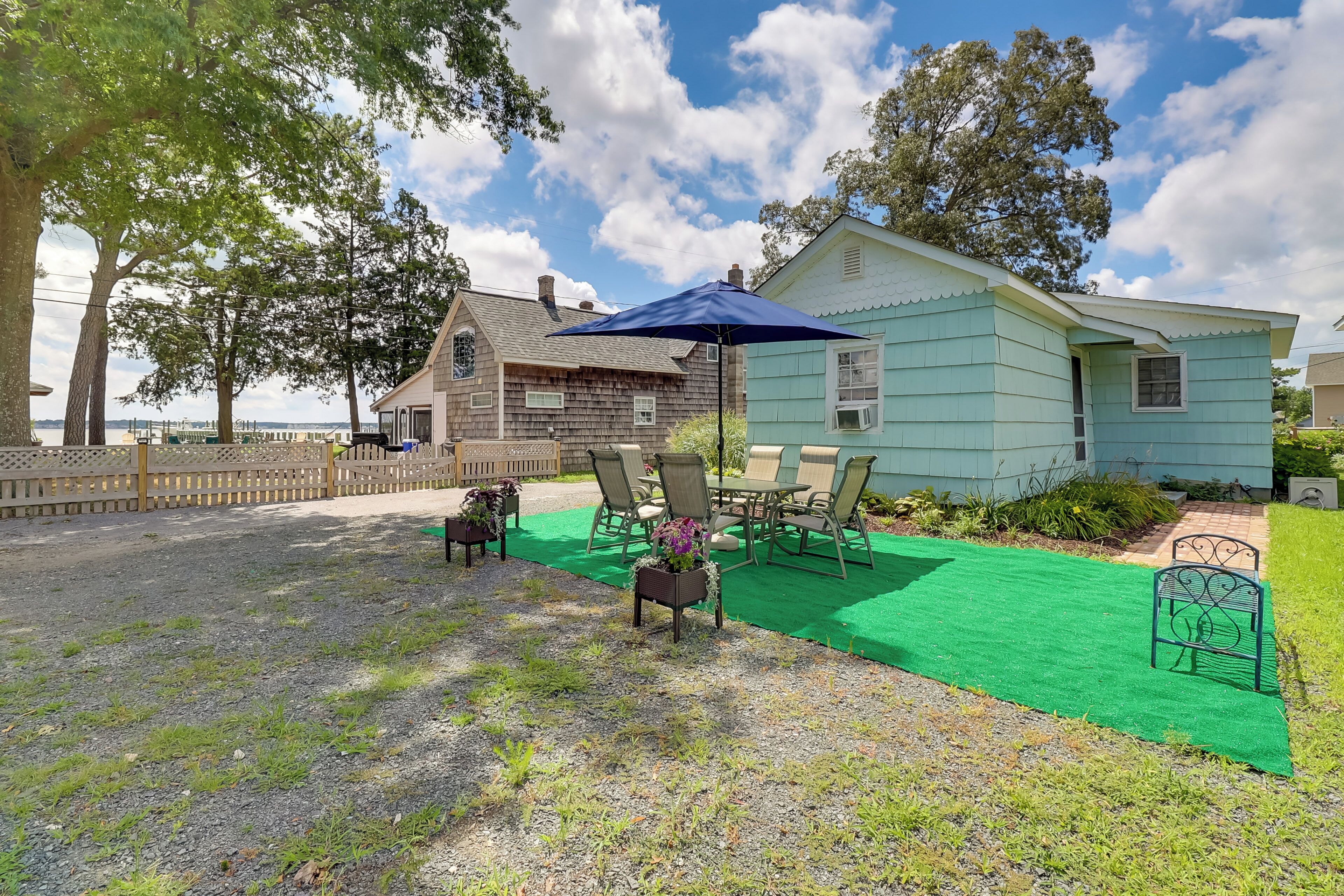 A house with a green lawn, outdoor furniture, and a blue umbrella.