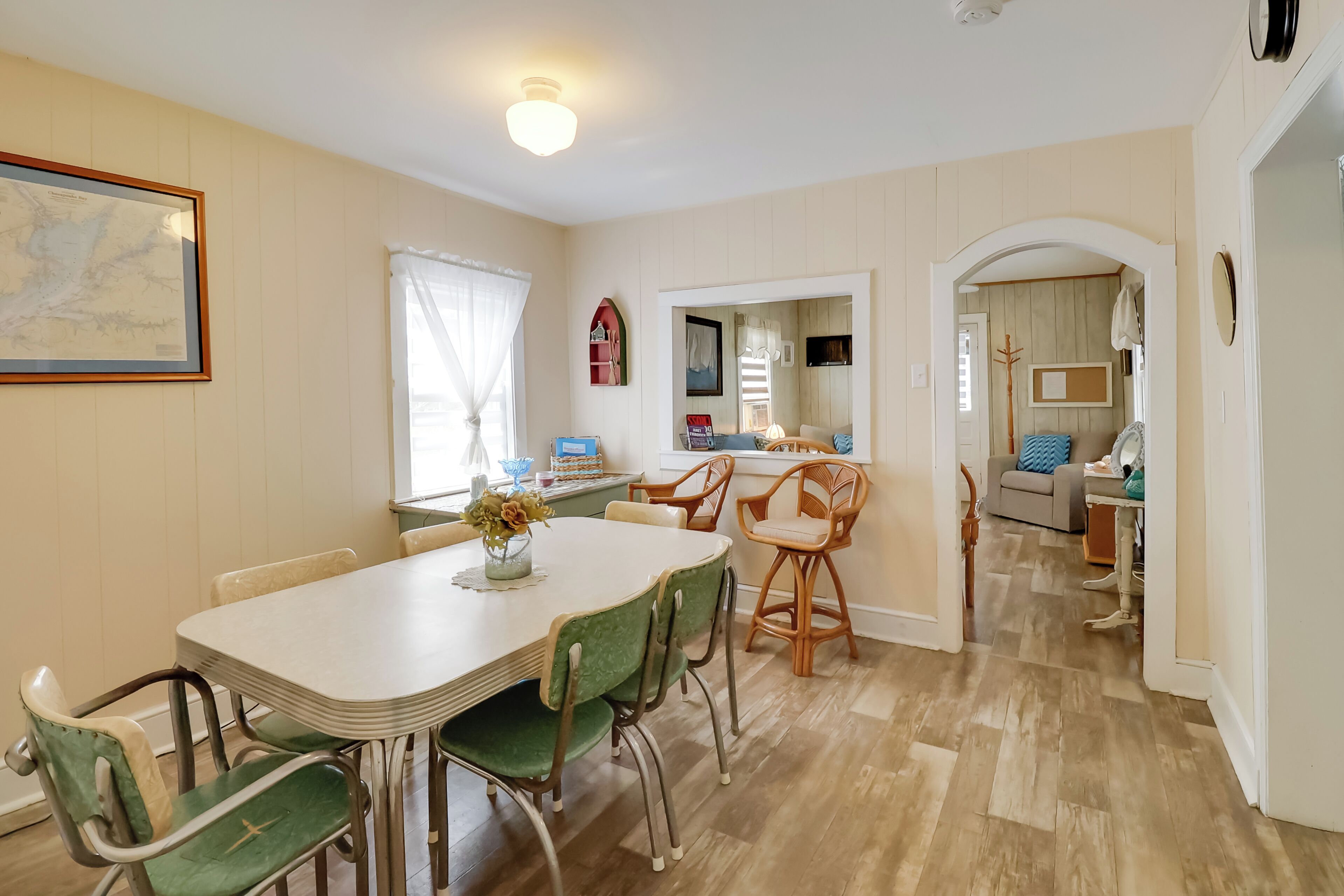 Un coin repas avec une table et des chaises, une carte accrochée au mur et une fenêtre avec des rideaux.