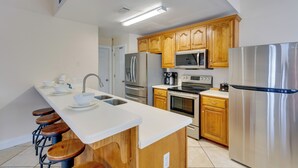 A modern kitchen with wooden cabinets, stainless steel appliances, and a white countertop. - Orange Beach Family Duplex w/ Deck < 1 Mi to Shore (Orange Beach)