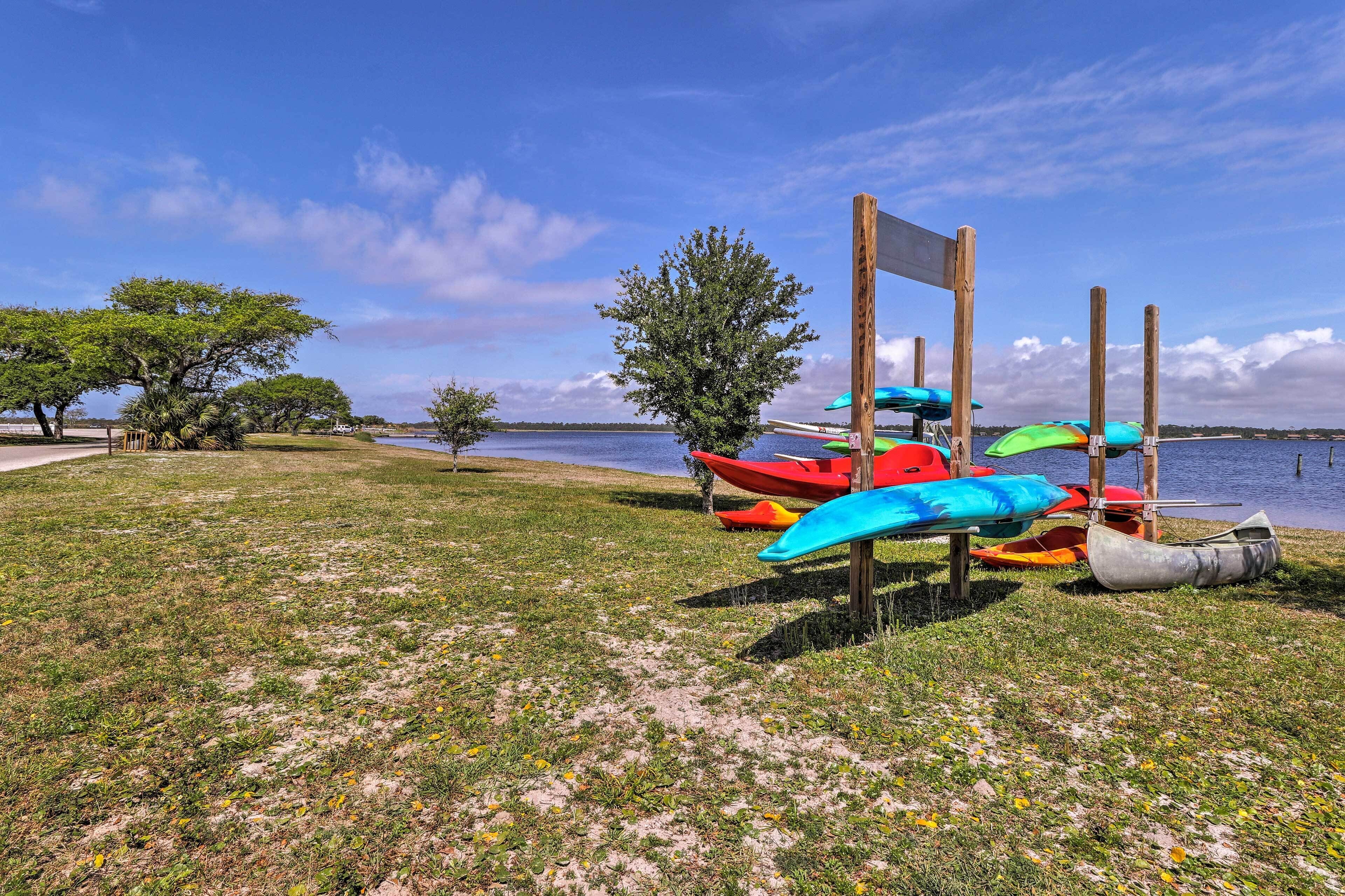 A grassy area with kayaks and a wooden signpost by a body of water.