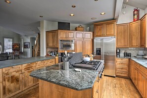 Een moderne keuken met houten kasten, granieten aanrechtbladen, roestvrijstalen apparatuur en een centraal eiland.