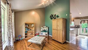 A room with wooden flooring, a cushioned bench, a wooden cabinet, a bookshelf, and a kitchenette area. - Family-friendly Coatesville House w/ Fire Pit (Coatesville)