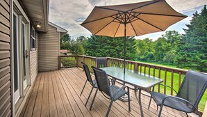 A wooden deck with a glass table and chairs, an umbrella, and a view of a green landscape. - Family-friendly Coatesville House w/ Fire Pit (Coatesville)
