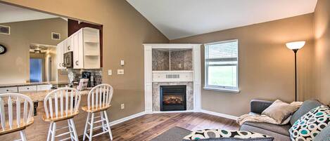 A living room with a fireplace, a sofa, and a dining area with chairs.