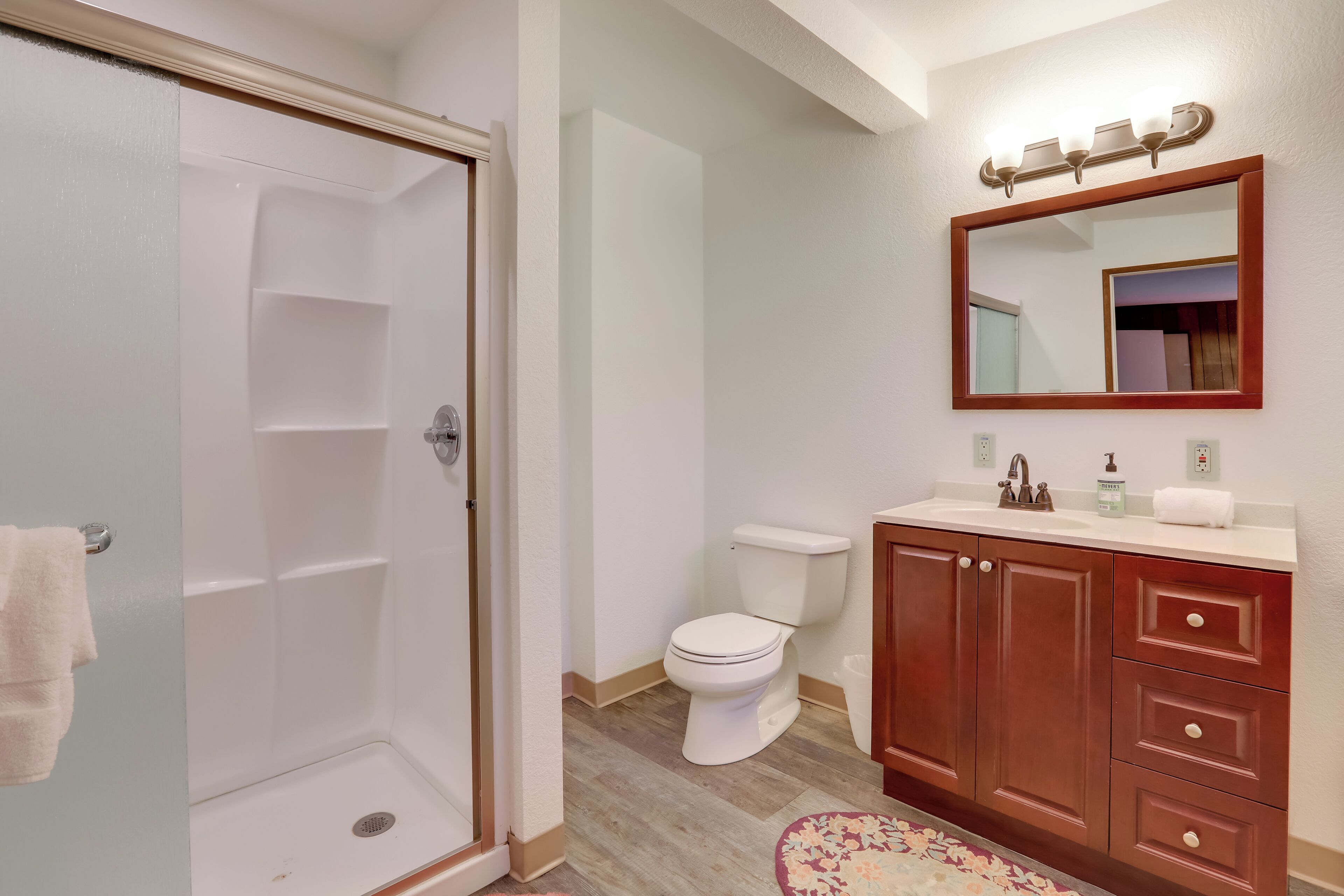 A bathroom with a shower, toilet, vanity with drawers, and a mirror.