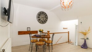 Un comedor con una mesa y sillas de madera, un reloj de pared y una lámpara colgante moderna.
