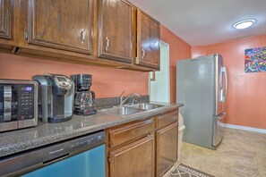 A kitchen with wooden cabinets, a stainless steel refrigerator, a coffee maker, and a dishwasher.