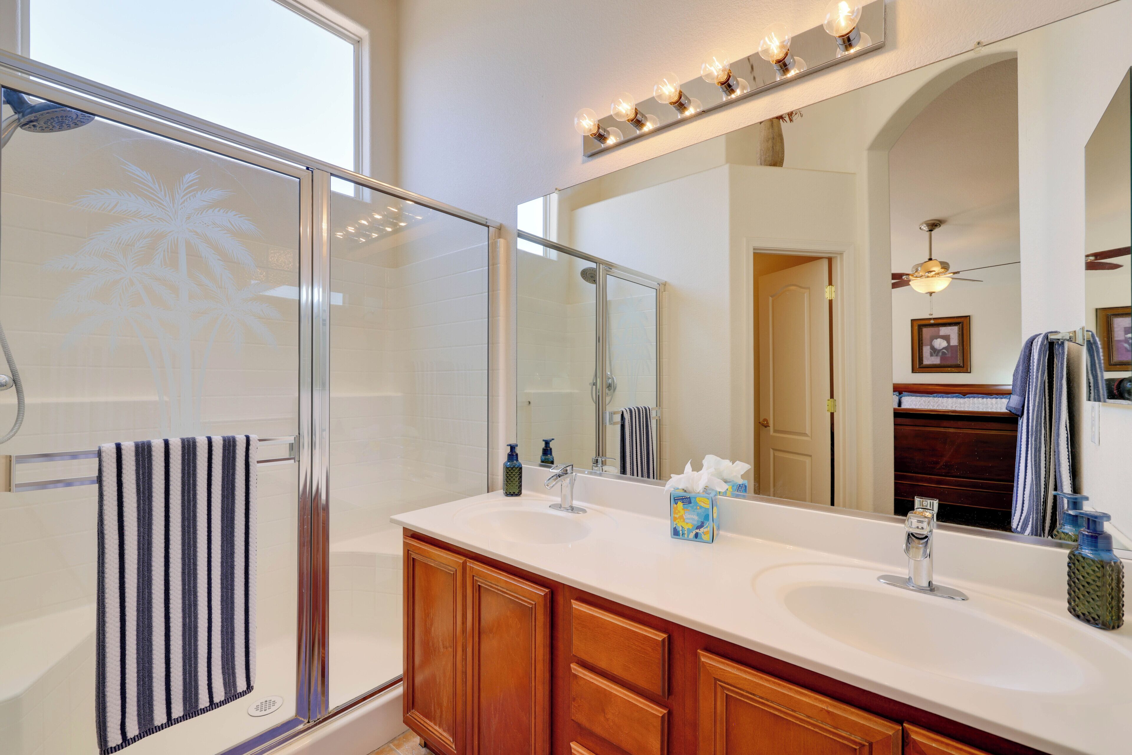 A bathroom with a glass shower enclosure, a large mirror, and a vanity with two sinks.