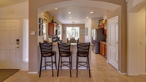 Una cocina con isla central, taburetes de bar y una mesa de comedor.