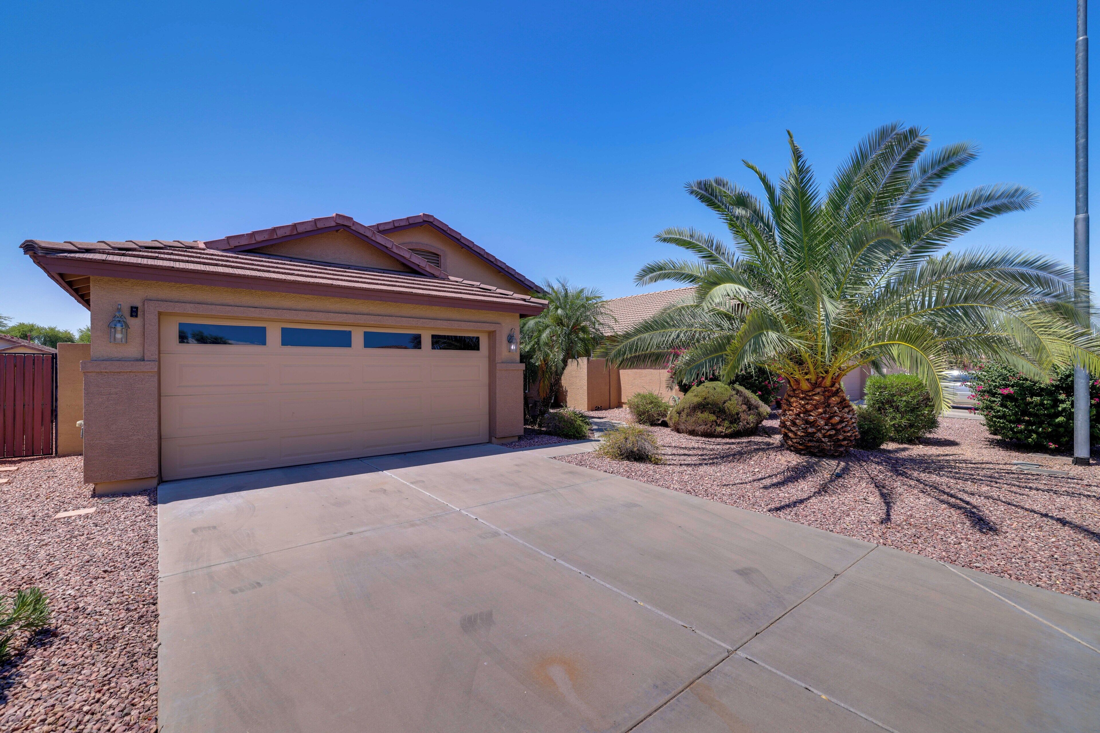 A single-story house with a garage, a driveway, and a palm tree.