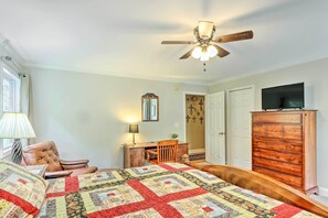 A bedroom with a large bed, a wooden dresser, a desk with a chair, a ceiling fan, and a television on a dresser. - Lake Chatuge Retreat w/ Dock & Mtn Views! (Hayesville)