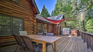 A wooden deck with a table and chairs, a barbecue grill, and a covered area with string lights. - 5 Mi to Hiking: Custom Cabin w/ Deck in Arnold! (Arnold)