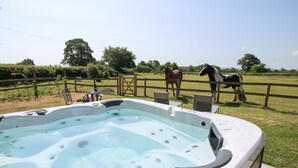 Un bain à remous entouré d’une clôture en bois, avec des chaises en arrière-plan.