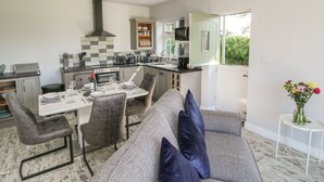 Une cuisine moderne avec un coin repas, une palette de couleurs grise et blanche, et une vue sur la verdure environnante.