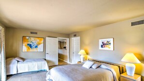 A hotel room with two beds, a door leading to a bathroom, and artwork on the walls. - Carefree Casita w/ Outdoor Pool & Mountain View! (Carefree)