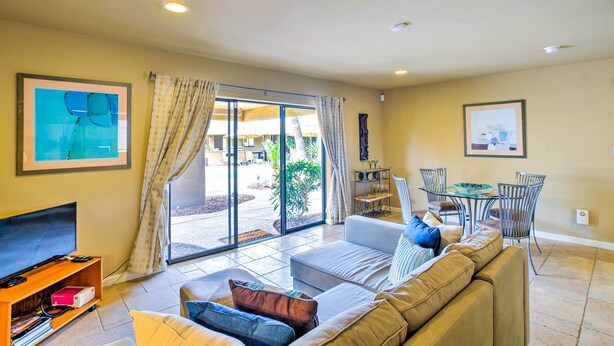A living room with a sofa, TV, and dining area with chairs and a table. - Carefree Casita w/ Outdoor Pool & Mountain View! (Carefree)