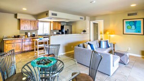 A modern kitchen with wooden cabinets, a dining area with a glass table, and a living room with a gray sofa. - Carefree Casita w/ Outdoor Pool & Mountain View! (Carefree)
