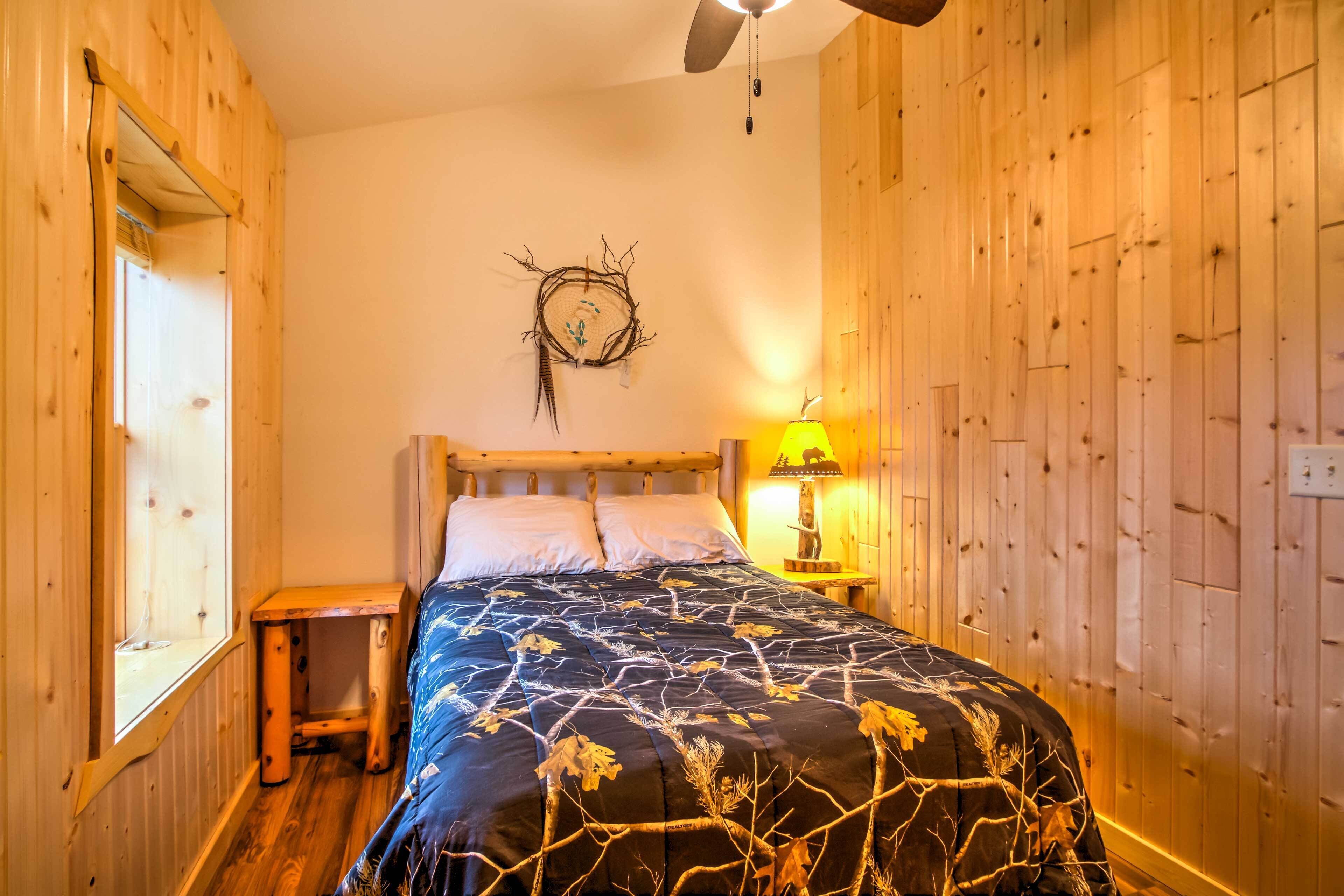 Una habitación con paneles de madera, una cama, una mesita de noche, una lámpara de pared y un ventilador de techo.