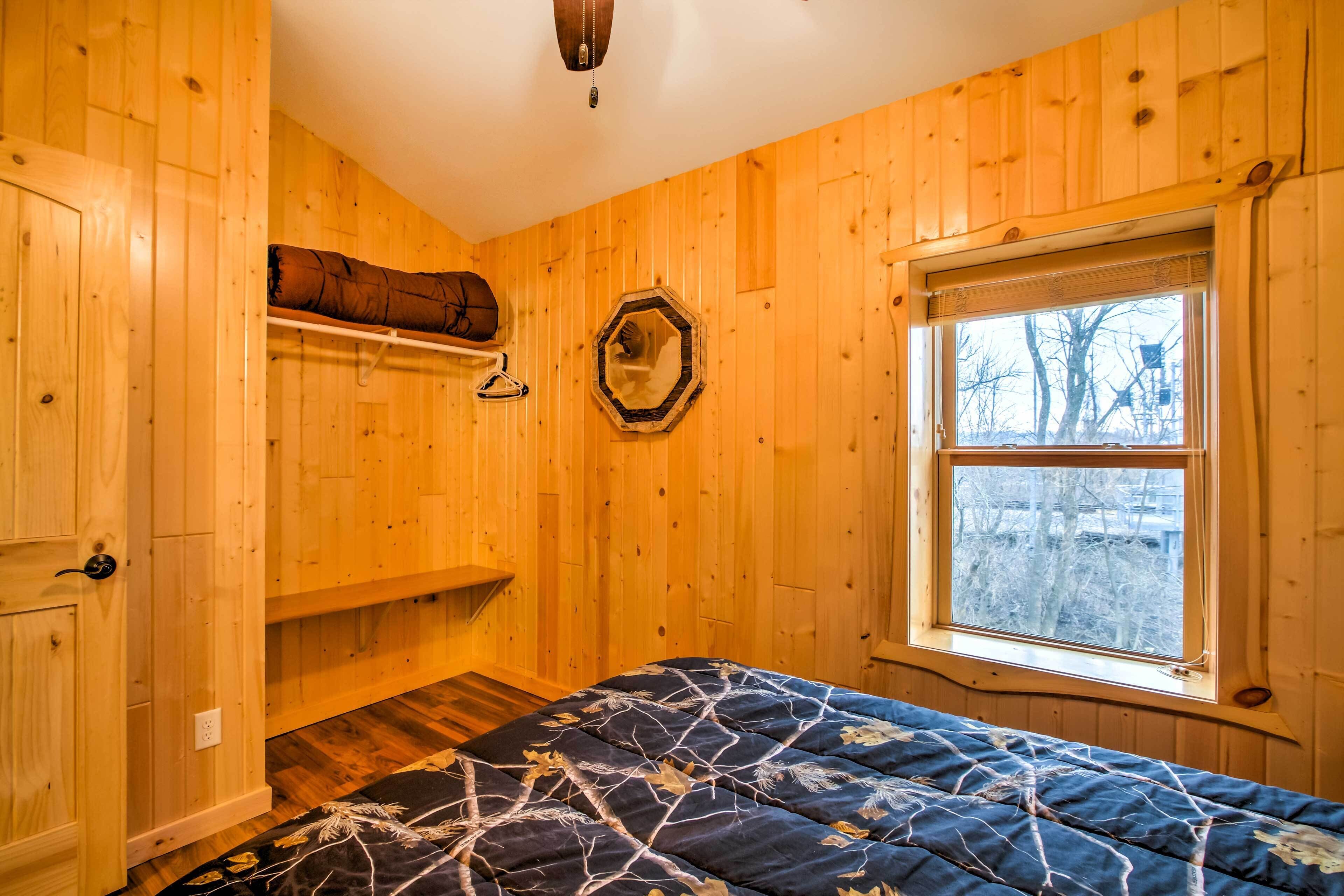 Una habitación de madera con una cama, una ventana y una estantería con una manta.
