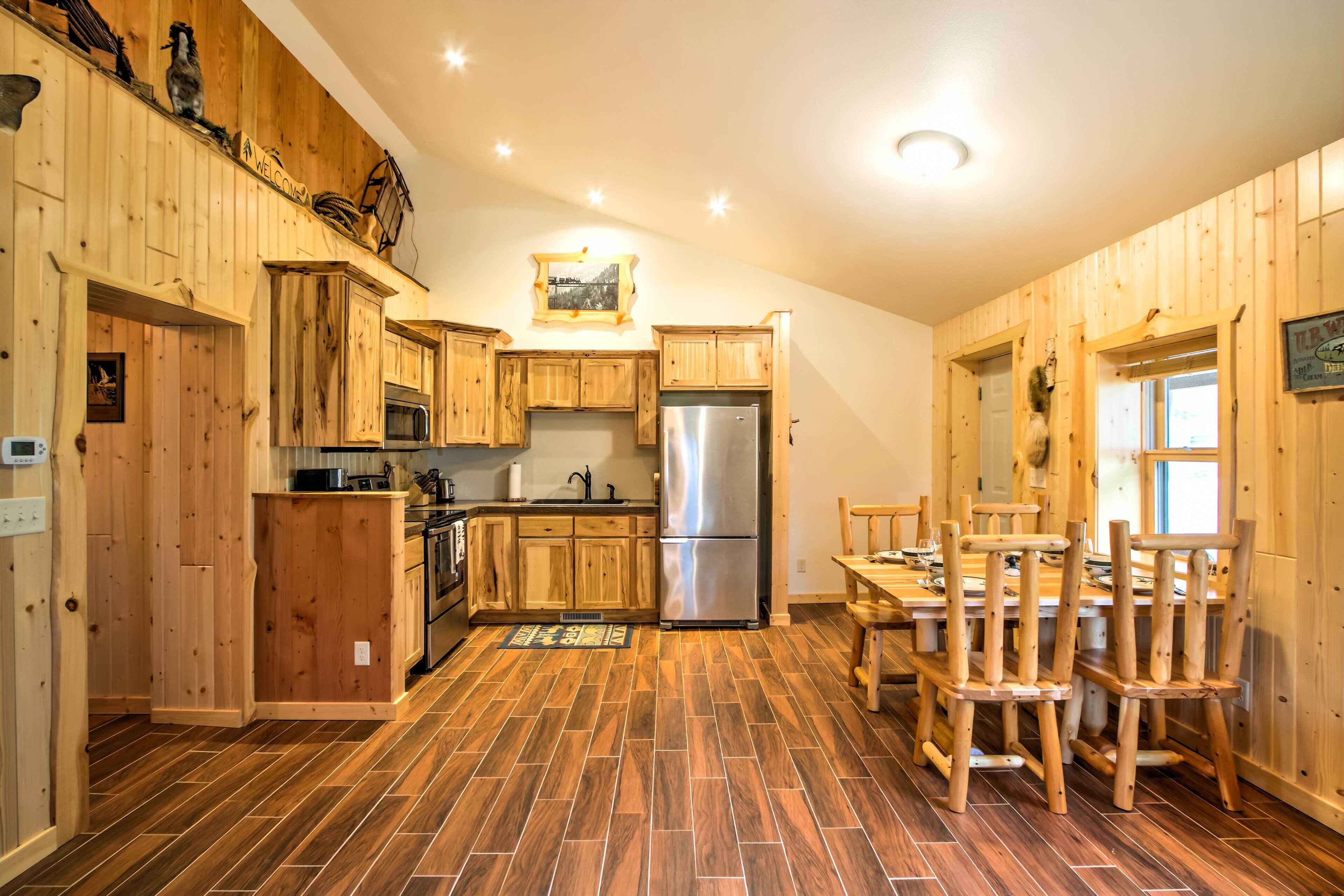 Una cocina con armarios de madera, un refrigerador de acero inoxidable y un comedor con sillas de madera.
