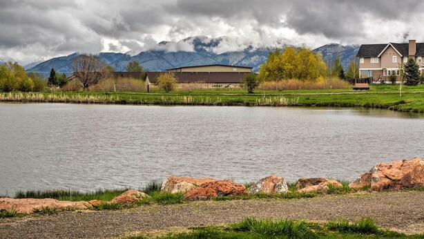 A lakeside view with a large building, mountains, and a clear sky.