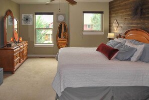 A bedroom with a large bed, a dresser, two windows, and a wooden headboard. - 'bozeman Getaway' w/ Mountain Views, Near Downtown (Bozeman)