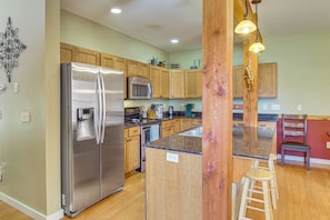 A kitchen with wooden cabinets, stainless steel appliances, a granite countertop, and a wooden stool. - 'bozeman Getaway' w/ Mountain Views, Near Downtown (Bozeman)