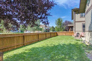 A residential backyard with a wooden fence, a lawn, and a house in the background. - 'bozeman Getaway' w/ Mountain Views, Near Downtown (Bozeman)