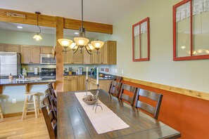 A dining area with a wooden table, chairs, and a chandelier. - 'bozeman Getaway' w/ Mountain Views, Near Downtown (Bozeman)