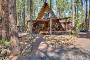 A cabin with a wooden exterior, a porch, and a gravel path leading to the entrance.