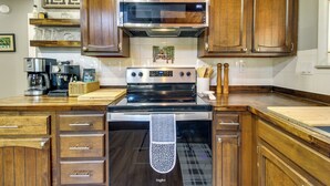 A kitchen with wooden cabinets, a stainless steel oven, and a coffee maker. - The Silly Goose A-frame Cabin in Pinetop-lakeside (Pinetop)