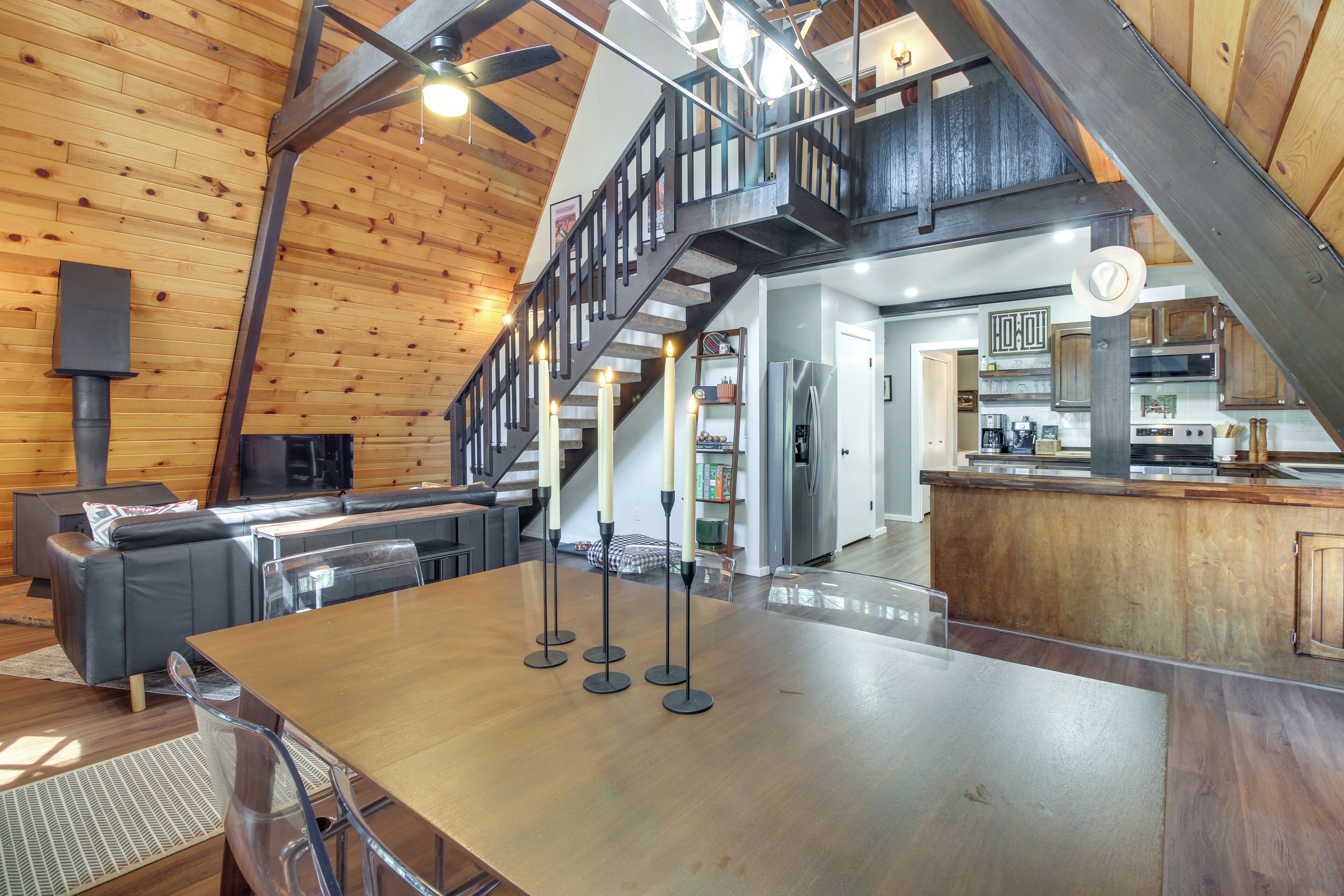 Un amplio espacio habitable con techo alto, una escalera de madera y una cocina moderna.