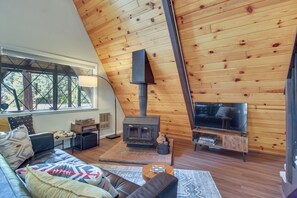 A cozy living room with a fireplace, leather sofa, and a large window.