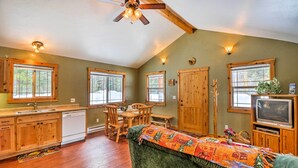 A cozy room with wooden furniture, a dining table, a sofa, and a ceiling fan. - Hungry Horse Cabin: 11 Mi to Glacier National Park (Hungry Horse)