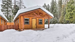 A wooden cabin with a snow-covered roof, surrounded by a wooden fence and snow-covered ground. - Hungry Horse Cabin: 11 Mi to Glacier National Park (Hungry Horse)