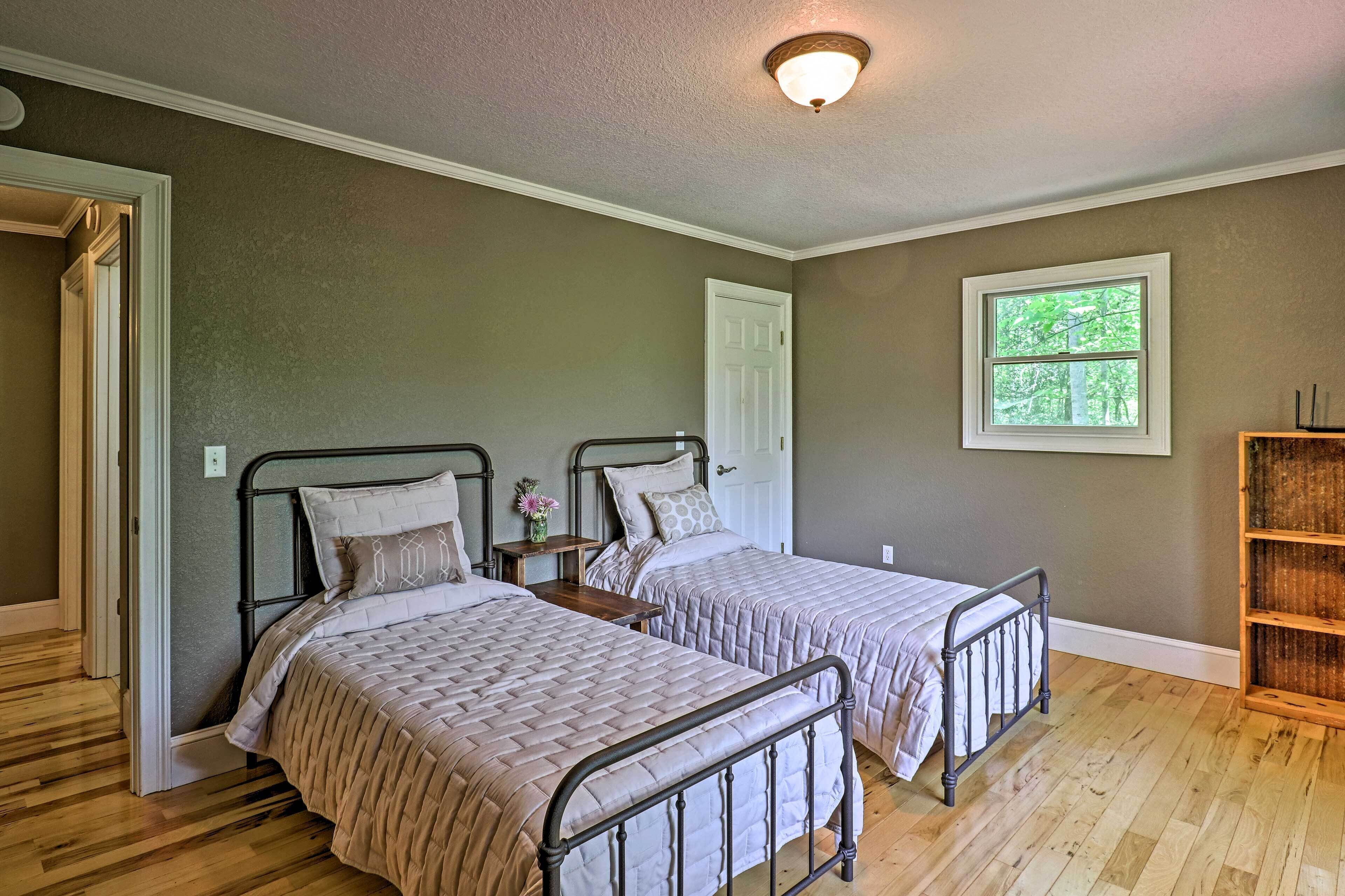 Quarto com duas camas, piso de madeira, janela e porta.