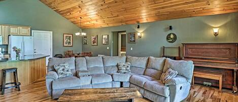 A living room with a sectional sofa, wooden coffee table, and a piano.