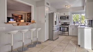 Una cocina moderna con gabinetes blancos, electrodomésticos de acero inoxidable y una isla integrada con taburetes.