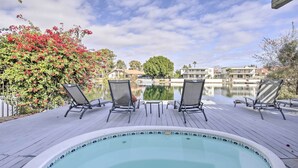 Piscina con sillas de descanso y vistas a edificios al otro lado del agua.