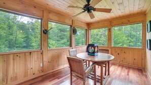 A wooden cabin with a round table and chairs, large windows, and a ceiling fan. - Rustic North Creek Getaway ~ 4 Mi to Gore Mtn! (North Creek)