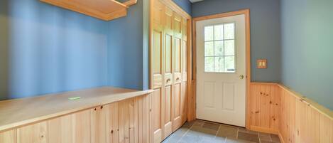 A hallway with wooden paneling, a door with a window, and a tiled floor.