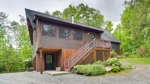 A two-story wooden cabin with a wooden staircase leading to a deck. - Rustic North Creek Getaway ~ 4 Mi to Gore Mtn! (North Creek)