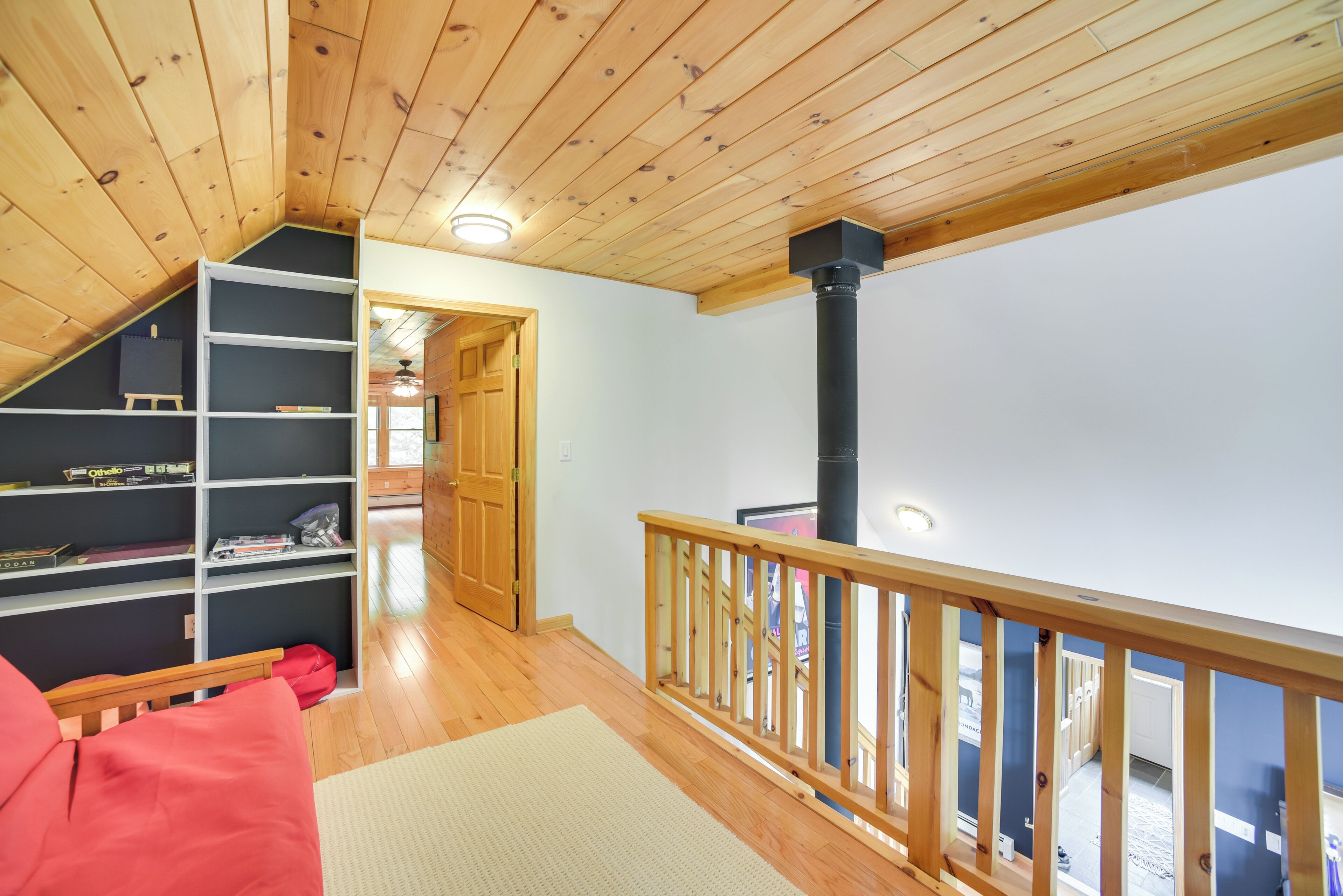 Een houten interieur met een trap, een boekenplank en een rode stoel.