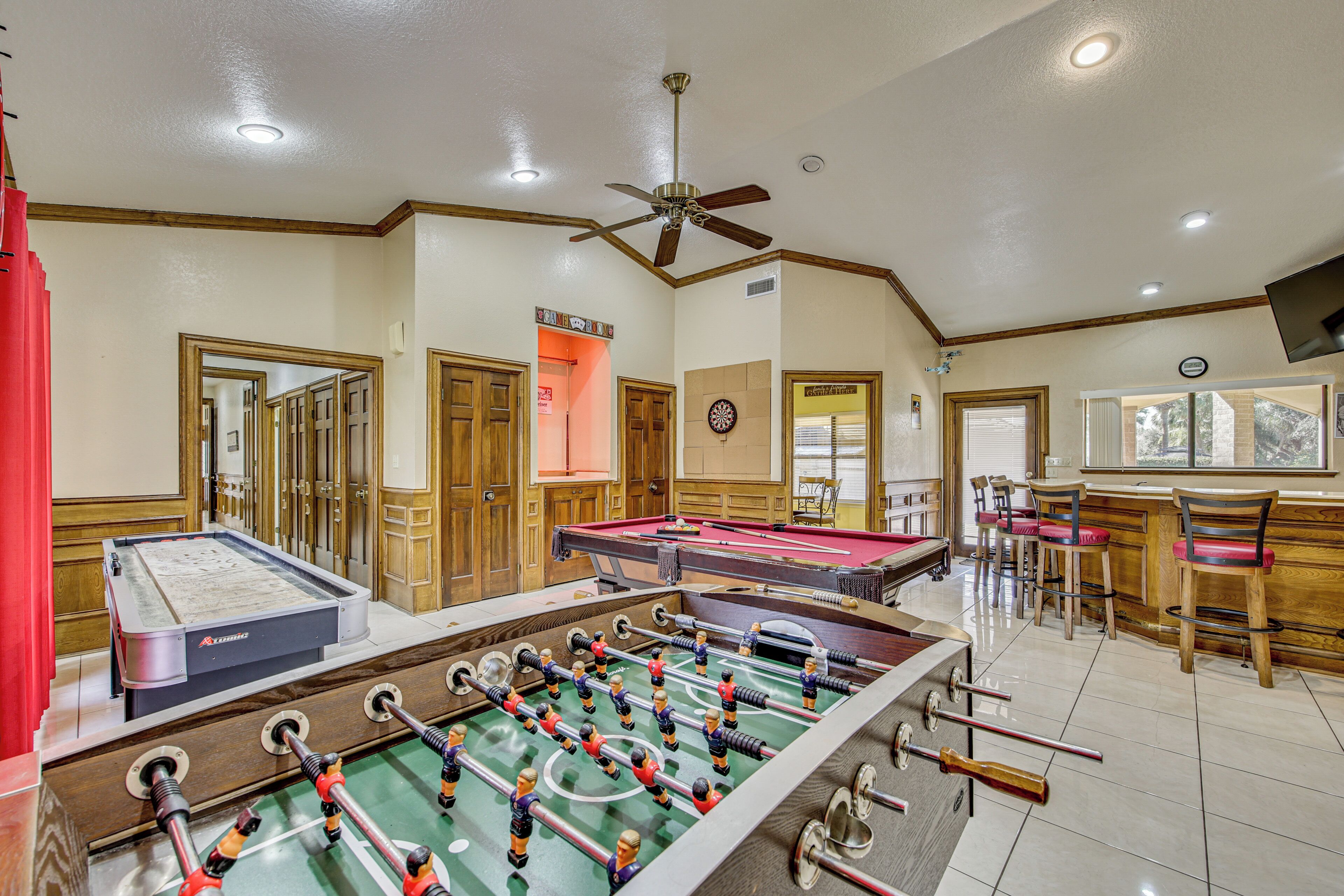 Una habitación con dos mesas de fútbol de mesa, una mesa de billar y una zona de bar con taburetes.