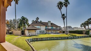 A two-story house with a large front yard and a pond. - Pool & Game Room: Waterfront Harlingen Home (Harlingen)