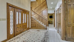 A hallway with wooden doors, a staircase, and a patterned carpet. - Pool & Game Room: Waterfront Harlingen Home (Harlingen)
