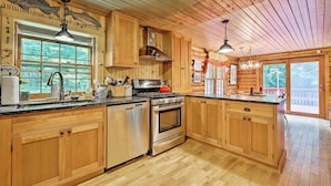 A wooden cabin kitchen with a large island, stainless steel appliances, and a view of the outdoors. - Private Wooded Cabin: 7 Mi to Mount Snow! (Wilmington)