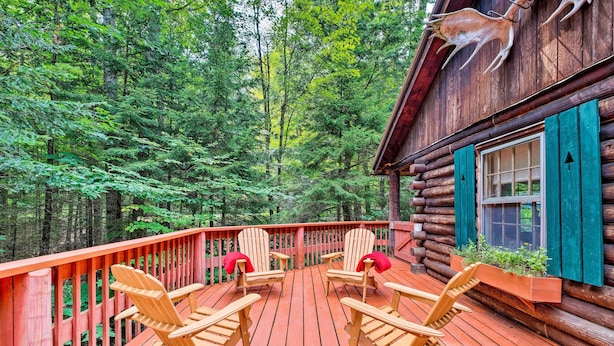 A wooden deck with Adirondack chairs, a wooden cabin with green shutters, and a forest backdrop. - Private Wooded Cabin: 7 Mi to Mount Snow! (Wilmington)